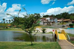 a bridge over a body of water with houses in the background at Chácara Helenna Colonetti in Lindóia