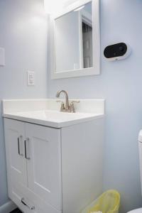 een witte badkamer met een wastafel en een spiegel bij Beautiful 3-bedroom home off-street parking. in Greensboro