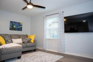 een woonkamer met een bank en een plafondventilator bij Beautiful 3-bedroom home off-street parking. in Greensboro