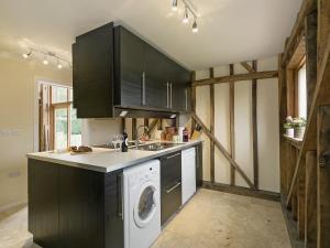 una cocina con armarios negros, lavadora y secadora en Chilsham Barn en Herstmonceux