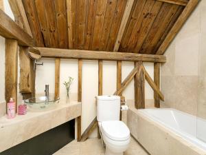 uma casa de banho com um WC, um lavatório e uma banheira em Chilsham Barn em Herstmonceux