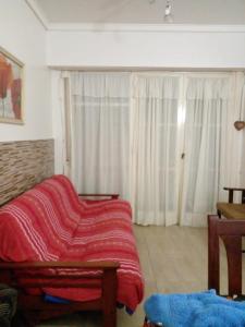 una sala de estar con una manta roja en un sofá en Departamento Isabel II en Mar del Plata