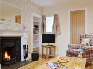 a living room with a fireplace and a television at Well Cottage in Ceres