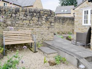 a wooden bench sitting in front of a stone wall at Linnets in Beaminster