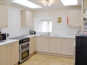 a kitchen with white cabinets and a stove top oven at Linnets in Beaminster