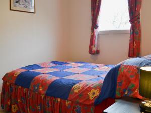 a bedroom with a quilt on a bed with a window at Little Whiteleigh in Week Saint Mary