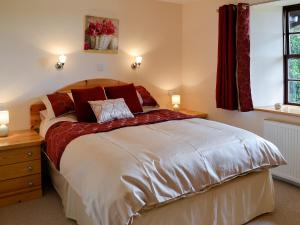 - une chambre avec un grand lit et des oreillers rouges dans l'établissement Bridge House - Ukc1340, à North Molton
