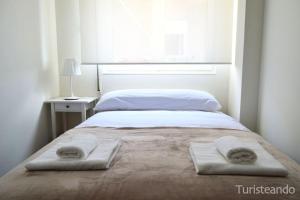 a bed with two towels on it with a window at APARTAMENTO BARLOVENTO in San Vicente de la Barquera