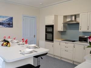 uma cozinha com armários brancos e um balcão branco em Bonshawside Farmhouse em Kirtlebridge