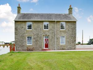 an old stone house with a red door and a bench at Bonshawside Farmhouse in Kirtlebridge