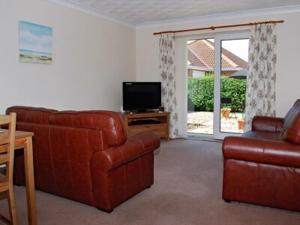 a living room with a couch and a television at Sea Breeze Bungalow in Sutton on Sea