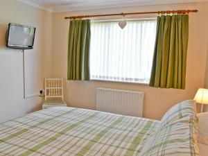 a bedroom with a bed and a television and a window at Sea Breeze Bungalow in Sutton on Sea