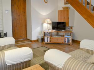 a living room with two chairs and a tv at Hay Loft -23894 in Aylmerton