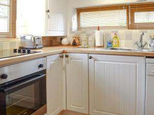 a kitchen with white cabinets and a sink at Hay Loft -23894 in Aylmerton