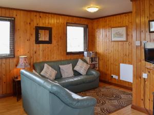 a leather couch in a living room with wood paneling at Finch Lodge - E4793 in Nawton