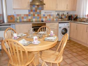 een keuken met een houten tafel met stoelen en een wasmachine bij Nellys Cottage in Lanehead
