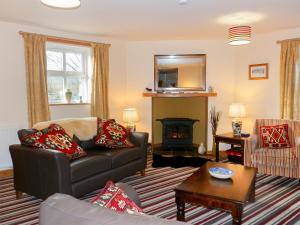 a living room with a couch and a fireplace at Nellys Cottage in Lanehead
