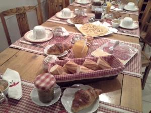 einen Tisch mit einem Frühstück mit Käsebrot und Orangensaft in der Unterkunft Chambres d'Hôtes Au Temps Des Cerises in Jumièges