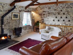 a living room with a leather couch and a fireplace at The Coach House - 24439 in Bodmin