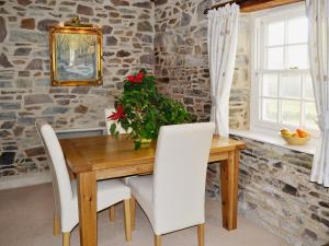 a dining room with a wooden table and white chairs at The Coach House - 24439 in Bodmin