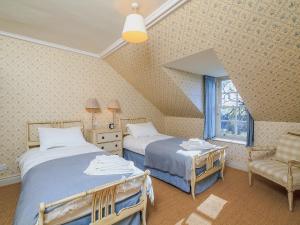 a bedroom with two beds and a chair and a window at The Glen Farmhouse in Crocketford