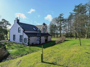 an old house on a hill with a grass field at The Glen Farmhouse in Crocketford
