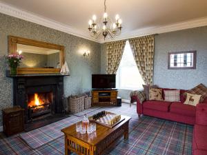 a living room with a fireplace and a red couch at Drummuie House in Golspie