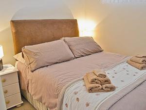 a bed with two towels on it with a night stand at Blue Waves in Perranporth