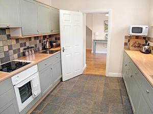 a kitchen with white cabinets and a stove top oven at Aira Cottage in Watermillock