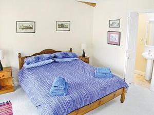 a bedroom with a bed with two blue towels on it at Aira Cottage in Watermillock