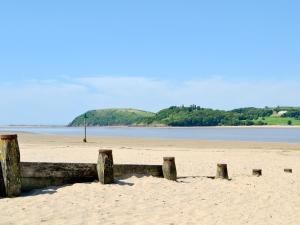 a beach with a wooden fence in the sand at The Cart Shed in Ferryside