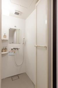 baño blanco con ducha y espejo en Great Access to Shibuya/Shinjuku-Gracias Shibuya, en Tokio