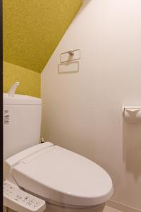 a bathroom with a white toilet and a yellow wall at Great Access to Shibuya/Shinjuku-Gracias Shibuya in Tokyo