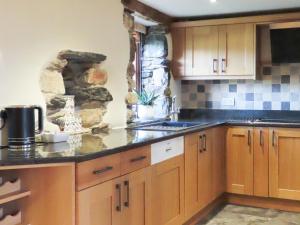 a kitchen with wooden cabinets and a stone wall at The Garth in Mungrisdale