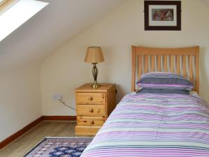 um quarto com uma cama e um candeeiro numa cómoda em Broomstick Cottage em Elsdon