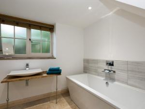 a white bathroom with a tub and a sink at The Coach House - Ukc2365 in Watton