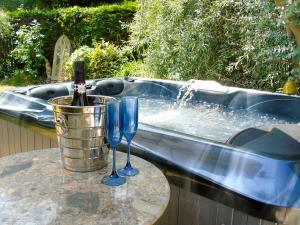 a tub with two wine glasses on a table at The Coach House - Ukc2365 in Watton