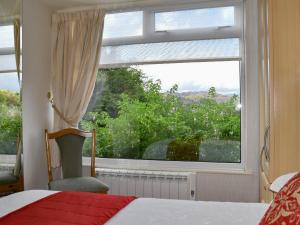 a bedroom with a window and a bed and a chair at Badgers Rake 7 in Ambleside