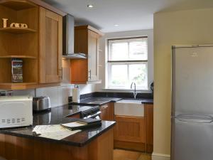 a kitchen with wooden cabinets and a white refrigerator at Raby Cottage-27764 in Wolsingham