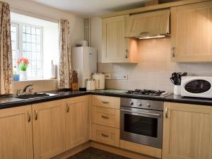 a kitchen with wooden cabinets and a stove and a microwave at Marlais in Llangadog