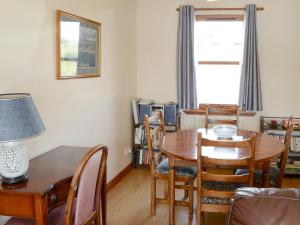 ein Esszimmer mit einem Tisch, Stühlen und einem Fenster in der Unterkunft Lochinchard Cottages in Kinlochbervie