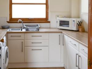 a kitchen with a sink and a microwave at Lochinchard Cottages in Kinlochbervie