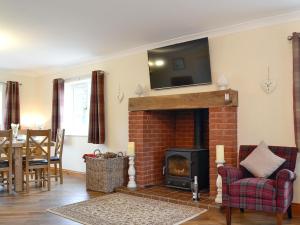a living room with a brick fireplace with a tv on the wall at Castle View in Llanbadarn-fynydd