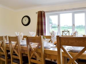 a dining room table with chairs and a clock on the wall at Castle View in Llanbadarn-fynydd