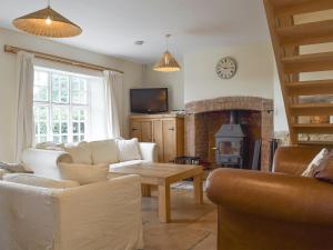 sala de estar con sofá, mesa y chimenea en South View Cottage, en Chadlington