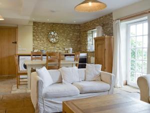 sala de estar con sofá blanco y cocina en South View Cottage, en Chadlington
