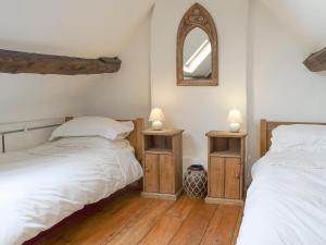 1 dormitorio con 2 camas y espejo en la pared en South View Cottage, en Chadlington