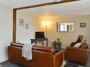 sala de estar con muebles de cuero y espejo en Caely Barn, en Penybont