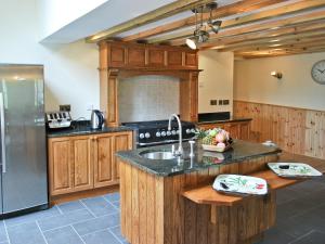 a kitchen with wooden cabinets and a stainless steel refrigerator at The Farmhouse in Llanarth