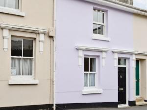 Casa blanca con puerta y ventanas moradas en Lavender Cottage, en Buckfastleigh